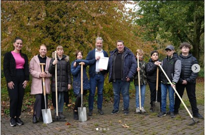 Frau Gündogdu als Berufswahlkoordinatorin (ganz links) ist hier die betreuende Person für die sieben Schüler*innen, welche hier mit einem Spaten zu sehen sind und ihre Zeit beim Bau des Grünen Klassenzimmers für ihre Berufswahlorientierung nutzen. In der Mitte des Fotos sind der Schulleiter Herrn Schnitker und Herr Kirchhoff von HerWe Galabau mit einer Kooperationsurkunde zu sehen.